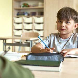 Schoolboy writing at school desk